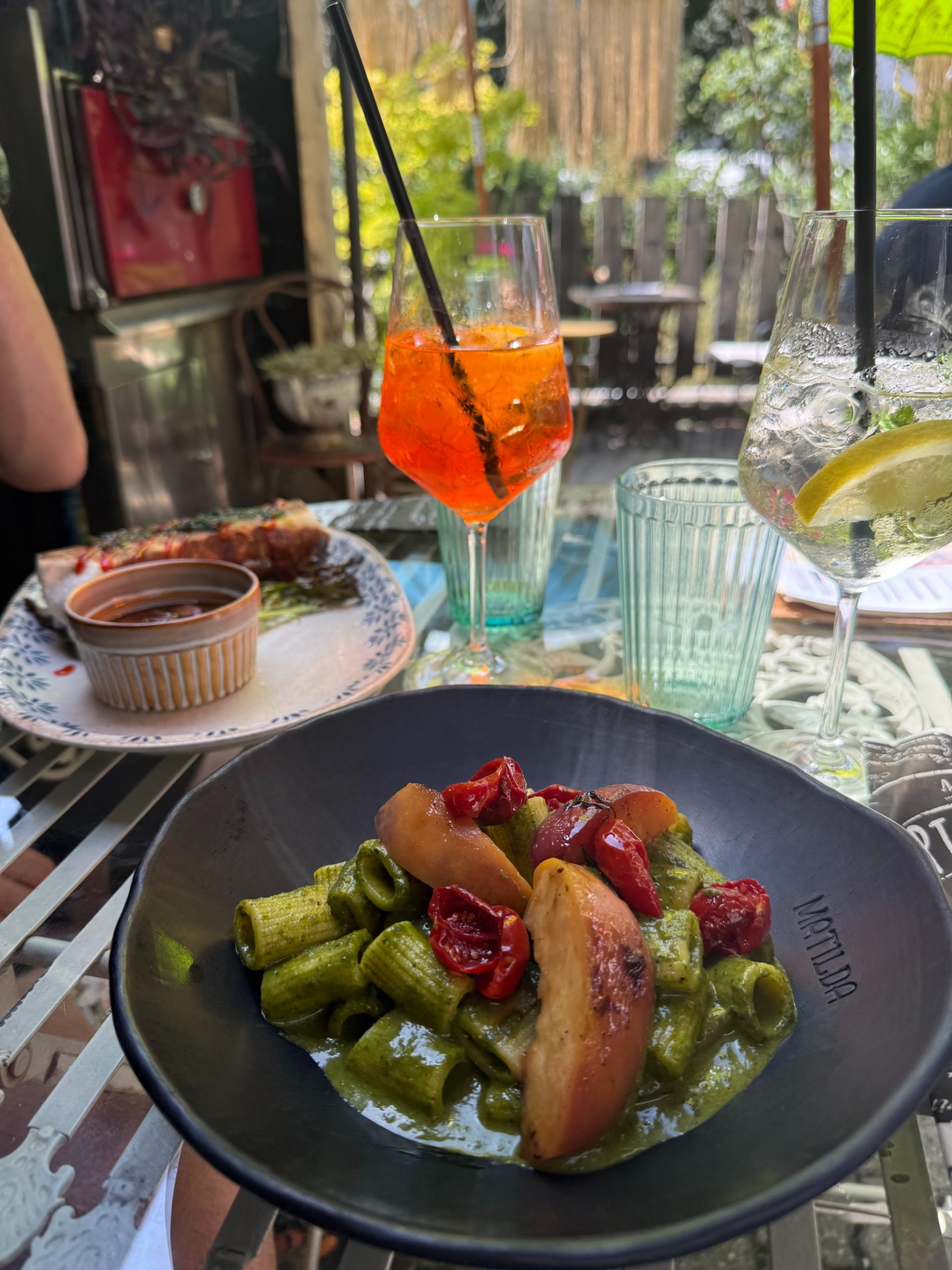 Aperitivo con aperol spritz y plato de pasta en una terraza durante la ruta
