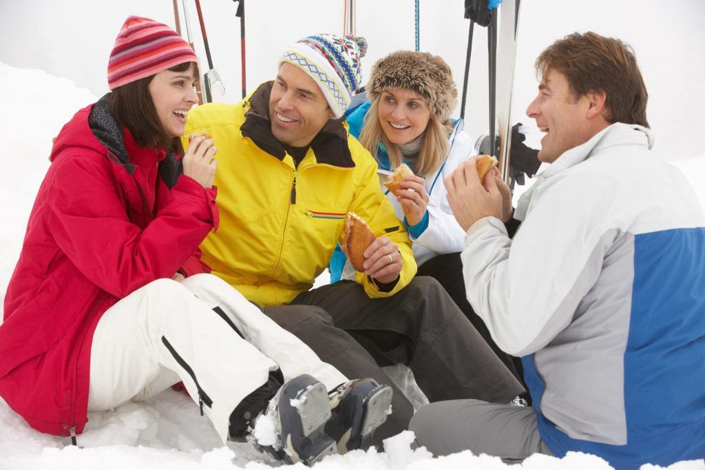 Amigos en su viaje de esquí comiendo fuera pistas